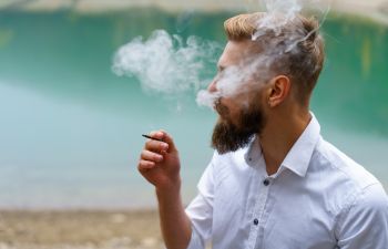 A bearded man smoking a cigarette.